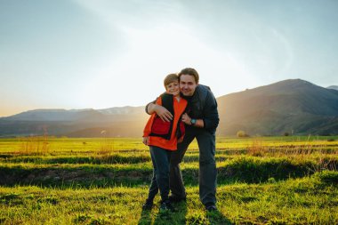 Baba ve oğul gün batımında pitoresk dağ vadisinde duruyorlar.