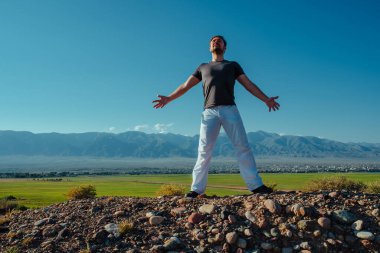 Genç adam yaz günü dağda dikilerek eğleniyor.