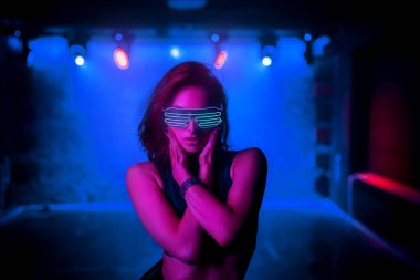 Parlak gözlüklü genç kadın neon tarzı kulüp portresi