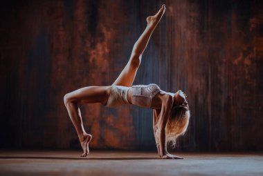 Paslı duvar arkasında gerinen genç kadın jimnastikçi.