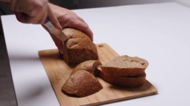 Beyaz masa manzaralı tahta üzerinde ekmek kesen bir adam.