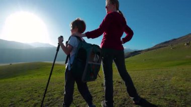 Çocuk turist ve annesi yaz günü dağlarda dikiliyorlar.