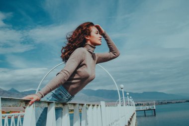 Gölün kıyısında köprüde poz veren romantik bir kadın.