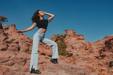 Genç ve güzel bir kadın yaz günü dağlarda poz veriyor.