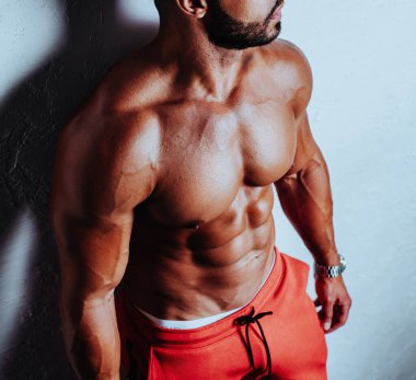 Beyaz arka planda güçlü bir vücut geliştiren genç adam.