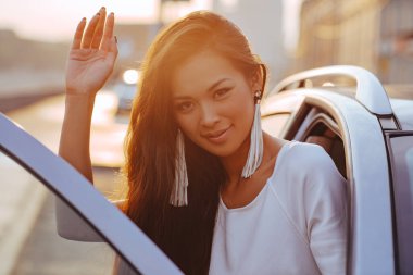 Şehir portresinde oturan genç bir kadın, ılık bir sabah ışığı.