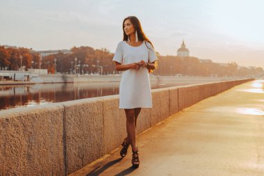 Genç Asyalı kadın güneşli bir sabahta taş iskelede yürüyor.