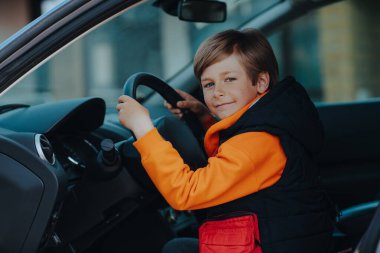 Çocuk sürücü koltuğunda oturuyor ve elinde direksiyon tutuyordu.