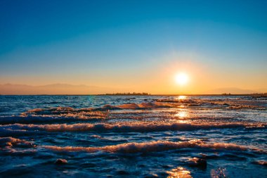 Gün batımında göl manzarası, göl kıyısında buzla kaplı kış manzarası.