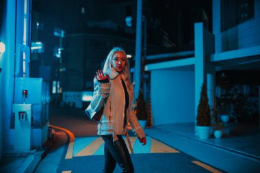 Genç, güzel, sarışın bir kadın Seul caddesinde yürüyor ve el sallıyor.