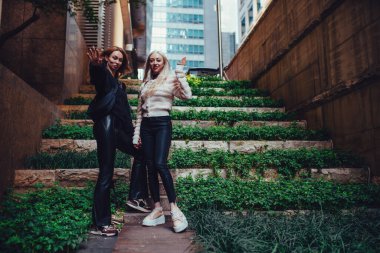 İki genç bayan arkadaş Seul yazında, şehir caddesinde el sallıyor.