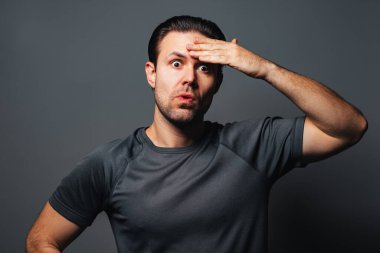 Gri arka planda genç yorgun adam duygusal portresi