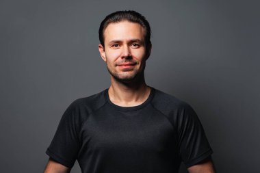 Gri arka plandaki yakışıklı gülümseyen adam stüdyo portresi