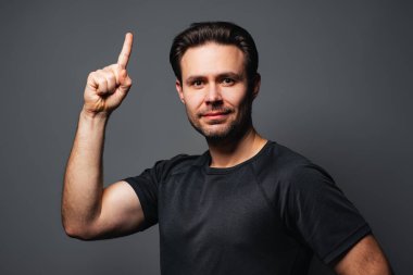 Genç ve yakışıklı bir adam, gri arka planda portresi var.