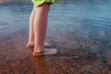 Çocuk sığ suda duruyor, bacakları yakın çekim