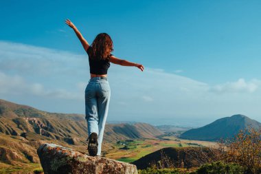 Yaz günü dağlarda yürüyen zayıf genç bir kadın.
