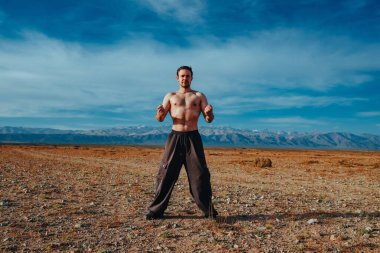 Genç ve güçlü adam yaz günü dağlarda dövüş sanatları eğitimi alıyor.