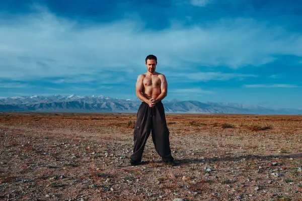 Genç ve güçlü adam yaz günü dağlarda dövüş sanatları eğitimi alıyor.