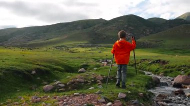 Çocuk turistler yaz günü pitoresk dağ vadisinde dere boyunca yürürler.