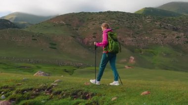 Genç kadın turist Picoresque dağ vadisinde akıntıyı geçiyor.