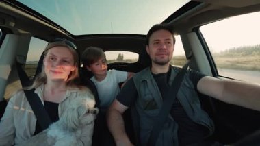 Köpek arabalı aile gün batımında yolda, araba manzaralı.