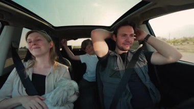 Köpek arabalı aile gün batımında yolda, araba manzaralı.