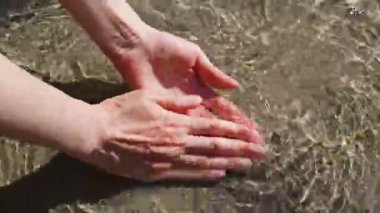 Genç kadın temiz dağ nehrinde ellerini yıkıyor.