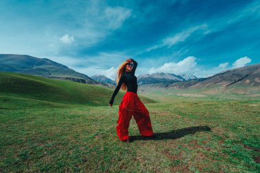 Genç ve güzel bir kadın dansçı yaz günü dağlarda poz veriyor.