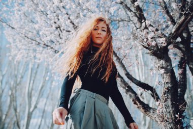 Bahar çiçekli ağacın altında duran kadının romantik portresi.