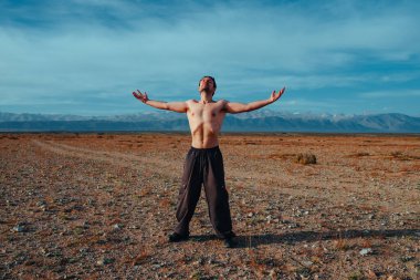 Genç güçlü adam yaz günü dağlarda spor antrenmanı yapıyor.