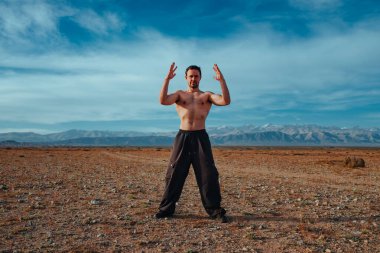 Genç ve güçlü adam yaz günü dağlarda dövüş sanatları eğitimi alıyor.