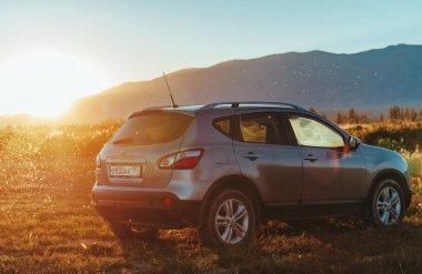 Kırgızistan - 03 Eylül 2024: Nissan Kashqai arabası sıcak gün batımı ışığında sonbahar sahasında duruyor