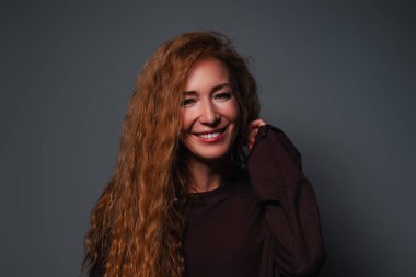 Gri arka planda genç, gülen kadın stüdyo resmi