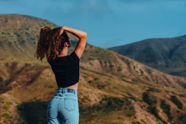 Yaz günü dağlarda poz veren zayıf genç bir kadın.