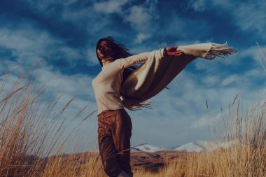 Genç, güzel Asyalı kadın, dağlarda arka planda dans ediyor.