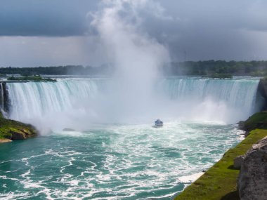 Ontario, Kanada - 22 AĞUSTOS 2018: Gri Dusky Günü 'nde Niagara Şelalesi' nin Kanadalı manzaralı, Atnalı Şelalesi 'nin sisli sisinde seyyar turist gezisi teknesi