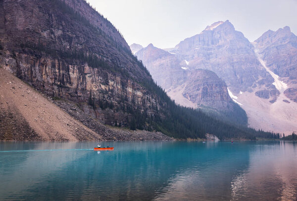 Alberta, Canada - AUGUST 4, 2021: Paddlers Canoeing in the Red Boat, Water Mirror of Moraine Lake, Banff