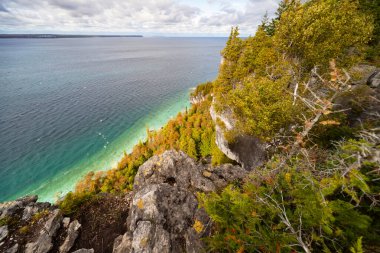 Huron Gölü turkuvaz kıyı şeridi. Etrafı kireçtaşı kayalıklarıyla çevrili. Ağaçlı kayalıklar, sonbahar günü manzarası, üst manzarası. 