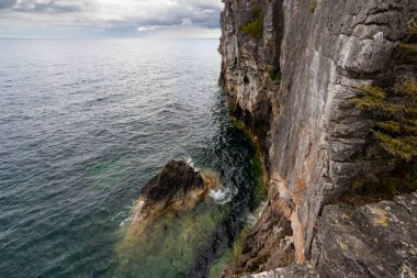 Huron Gölü 'nün Turkuaz Suyu ile çevrili Kireçtaşı Duvarlı Uçurum, Ontario, Kanada' daki Indian Head Trail 'de fırtınalı bir sonbahar gününde dikey çekim. 