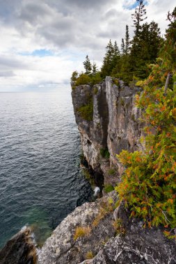 Huron Gölü 'nün Turkuaz Suyu ile çevrili Kireçtaşı Duvarlı Uçurum, Ontario, Kanada' daki Indian Head Trail 'de fırtınalı bir sonbahar gününde dikey çekim. 