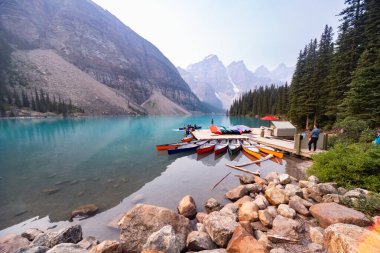 Alberta, Kanada - 4 AĞUSTOS 2021: Turistler Moraine, Banff gölünün sularında kanoda kürek çekmek için tekneye binmeyi bekliyorlar