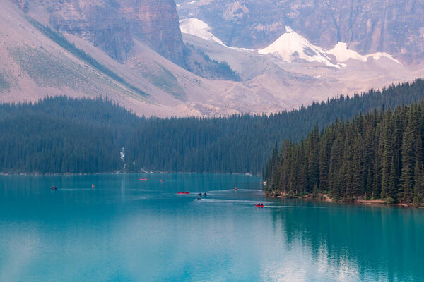 Alberta, Canada - AUGUST 4, 2021: Group of Paddlers Canoeing on the Still Water Mirror of Moraine Lake, Banff National Park, Alberta, Canada