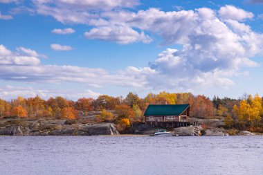 Ontario, Kanada - 10 Ekim 2020: Rugged Lake Shore Cliff 'teki Sonbahar Ormanı' nın ortasındaki Yalnız Kütük Kulübesi. Killarney, Ontario, Kanada yakınlarında güneşli bir sonbahar günü
