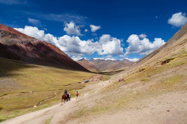 Gökkuşağı Dağı, Peru - 12 Mayıs 2018: Sırt çantası Turist Yürüyüşçüleri ve At Sürücüsü Kamp Yolundaki Gökkuşağı Dağı 'ndan iniyor. Vinicunca Park 'ta güneşli bir bahar günü, Peru, Real Colours