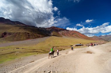 Gökkuşağı Dağı, Peru - 12 Mayıs 2018: Sırt çantası Turist Yürüyüşçüleri ve At Sürücüsü Kamp Yolundaki Gökkuşağı Dağı 'ndan iniyor. Vinicunca Park 'ta güneşli bir bahar günü, Peru, Real Colours