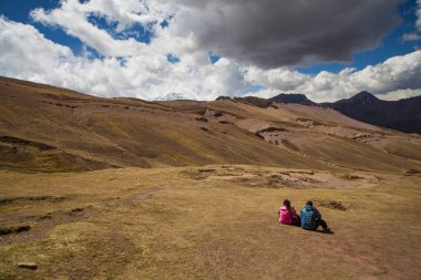 Gökkuşağı Dağı, Peru - 12 Mayıs 2018: Peru 'nun Gökkuşağı Dağı yakınlarındaki Vinicunca Parkı' ndaki dağların nefes kesici manzarasına oturan yürüyüşçüler hayran kaldılar. Güneşli Rüzgarlı Bahar Günü.