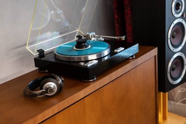 Klasik Stereo Turntable Plak Oynatıcı Mavi Disk, Kulaklıklar ve Gümüş Ağırlık Klempi, Tahta Konsol Cadenza 'da oturan, Sağdaki Siyah Hoparlör