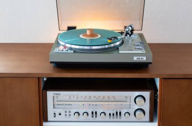 Ontario, Kanada - 8 Haziran 2025: AKAI Vintage Stereo Turntable Renkli Disk ve Ağırlık Kıskacıyla Tahta Konsol Cadenza ve İçerideki Alıcı
