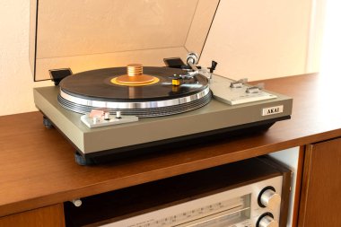 Ontario, Kanada - 8 Haziran 2025: AKAI Vintage Stereo Turntable Renkli Disk ve Ağırlık Kıskacıyla Tahta Konsol Cadenza ve İçerideki Alıcı