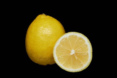 Image of a ripe lemon and a cut part of it on a black background